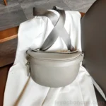 sac banane femme chic en cuir grainé gris taupe posé sur une chais à plat