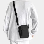 sac banane bandoulière homme noir porté dans le dos avec un style sportswear