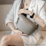 sac banane femme chic en cuir grainé gris taupe porté entre deux mains