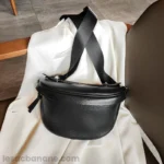 sac banane femme chic en cuir grainé noir brillant ciré posé sur une chais à plat