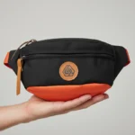 sac-banane-homme-tendance-noir-orange-main sac banane homme tendance noir et orange bicolor porté sur une main
