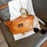 sac-banane-xxl-femme-cuir-graine-marron-orange sac banane xxl femme cuir grainé orange marron posé sur une chaise