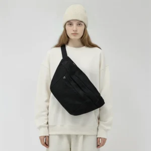 grand sac banane velours côtelé noir porté par une femme en bandoulière au style streetwear