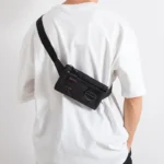 petit-sac-banane-noir-porte-en-bandouliere-dans-le-dos-par-un-homme petit sac banane noir porté en bandoulière par un homme