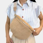 sac banane daim beige chaud porté en bandoulière par une femme