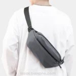 sac banane étanche gris porté en bandoulière dans le dos par un homme