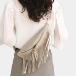 sac-banane-frange-beige-bandouliere-femme-dos sac banane frange beige porté en bandoulière par une femme dans le dos