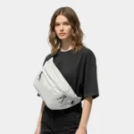 sac banane grand format gris clair porté en bandoulière par une femme