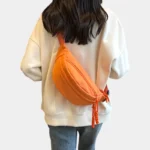 sac-banane-orange-bandouliere-dos-femme sac banane orange porté en bandoulière dans le dos d'une femme