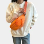 sac-banane-orange-bandouliere-femme-face sac banane orange porté en bandoulière par une femme vue de face