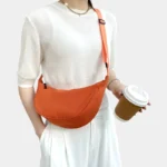 sac-banane-tendance-orange-corail-bandouliere-femme sac banane tendance couleur orange corail porté en bandoulière par une femme