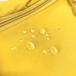 Sac banane jaune en polyester gros plan vu de face avec tissu déperlant et gouttes d’eau sur la surface