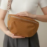 Sac Banane Bandouliere Velours marron porté en main avec une texture côtelée et une bandoulière à motifs en zigzag