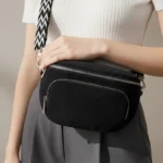 Sac Banane Bandouliere Velours noir porté en main avec une texture côtelée et une bandoulière à motifs