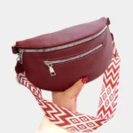 sac banane sangle interchangeable rouge bordeaux dans la main d'une femme