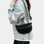 Petit Sac Banane Velours Côtelé Bandoulière Femme noir porté sur l'épaule avec une lanière en nylon