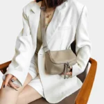 Sac à Main Banane Cuir Femme beige avec une bandoulière portée en travers du corps par une femme en veste blanche