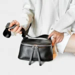 Sac à Main Banane Cuir Femme en cuir noir avec bandoulière porté dans une main