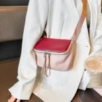 Sac à Main Banane Cuir Femme en cuir rose et bordeaux porté en bandoulière avec une boisson