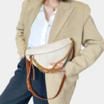 Sac Banane Femme Cuir Chaîne Dorée beige avec détails dorés et bruns Sac Banane Femme Cuir Chaîne Dorée de couleur beige avec des détails dorés et bruns porté à la main