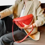 Sac Banane Femme Cuir Chaîne Dorée rouge avec style chic porté à la main Sac Banane Femme Cuir Chaîne Dorée couleur rouge porté à la main avec une tenue chic et moderne
