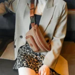Sac Banane Femme Cuir Chic Bicolore Sac Banane Femme Cuir Chic Bicolore en cuir beige et marron porté en bandoulière avec une veste chic