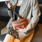 Sac Banane Femme Cuir Chic Bicolore marron élégant porté en bandoulière avec un style chic Sac Banane Femme Cuir Chic Bicolore marron porté en bandoulière avec un style élégant devant une veste beige