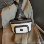 Sac Banane Femme Cuir Chic Bicolore noir et blanc avec poche zippée Sac Banane Femme Cuir Chic Bicolore en noir et blanc avec poche zippée posé sur un vêtement
