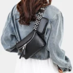 Sac Banane Femme Cuir Chic Rectangulaire noir avec bandoulière à motifs Sac Banane Femme Cuir Chic Rectangulaire en cuir noir avec une bandoulière à motifs porté sur l'épaule d'une femme