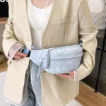 Sac Banane Velours Lisse bleu ciel tendance porté en bandoulière avec un style chic Sac Banane Velours Lisse de couleur bleu ciel porté en bandoulière avec un costume chic sur un fond moderne