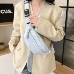Sac Banane Velours Lisse gris clair porté en bandoulière avec veste beige Sac Banane Velours Lisse de couleur gris clair porté en bandoulière avec une veste beige
