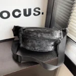 Sac Banane Velours Lisse noir avec sangle tressée posé sur une surface en bois Sac Banane Velours Lisse noir posé sur une surface en bois avec une sangle tressée