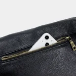 Sac Banane XL Cuir en cuir noir avec une fermeture éclair ouverte et un smartphone visible dans la poche arrière