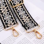 Bandoulière Motifs Jacquard Nordique avec mousquetons dorés, détails tissés noirs et beiges sur fond blanc.