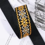 Bandoulière Motifs Jacquard Nordique avec motifs orange et blancs sur fond noir, texture tissée raffinée.