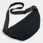 Sac banane velours côtelé noir posé à plat, vu de dessus avec sangle noire et boucle clip en plastique