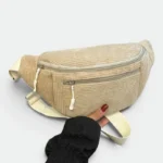 Sac banane velours côtelé beige sablle posé de face, tenu par une main avec deux fermetures éclair apparentes