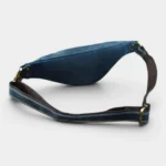 Petit sac banane cuir bleu posé à plat vue arrière, avec sangle épaisse et boucles en métal