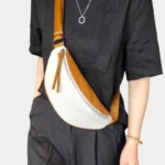 Sac banane cuir grainé bicolore blanc et camel porté en bandoulière par une femme de face