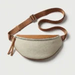 Sac banane cuir grainé femme demi-lune beige et marron posé de face, avec sangle marron et fermeture zippée argentée