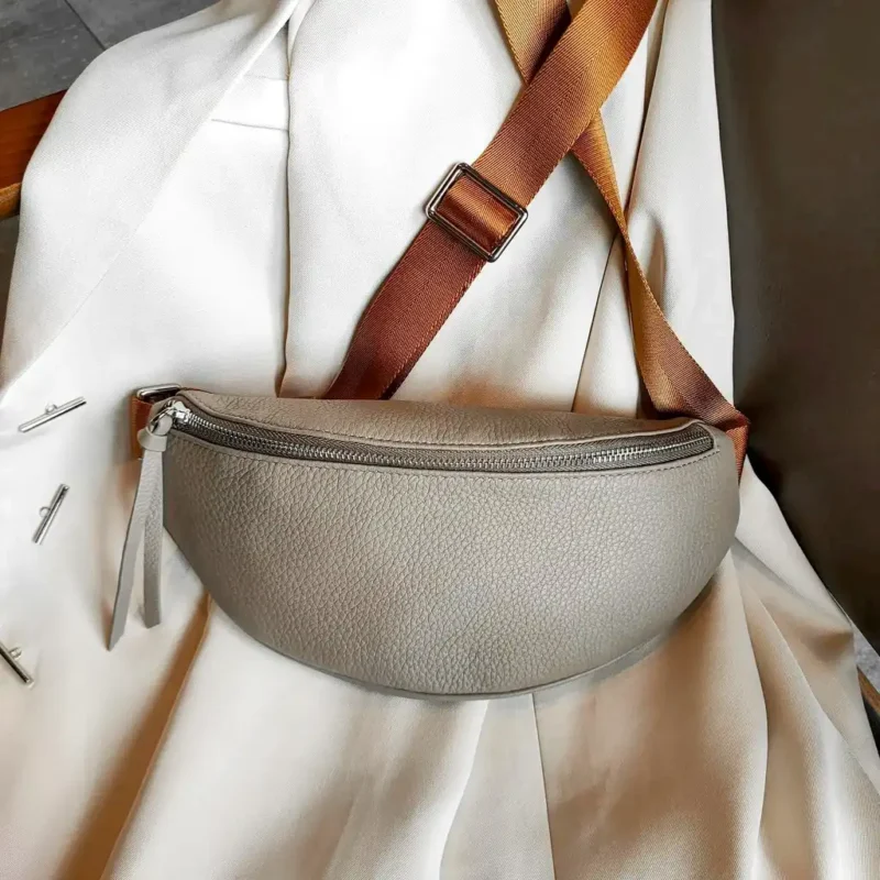 Sac banane cuir grainé femme gris posé de face, avec large sangle bicolore et fermeture chromée