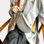 Sac banane cuir grainé gris porté en bandoulière par une femme au style décontracté, avec sangle large jaune