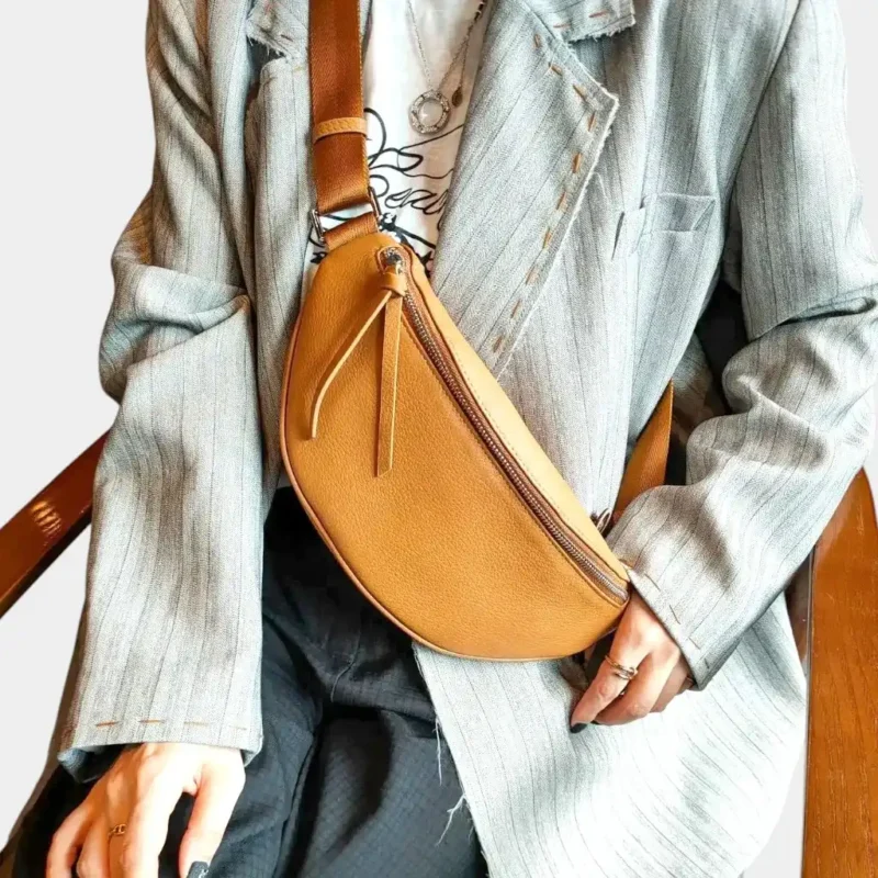 Sac banane cuir grainé femme demi-lune camel porté en bandoulière par une femme au style chic