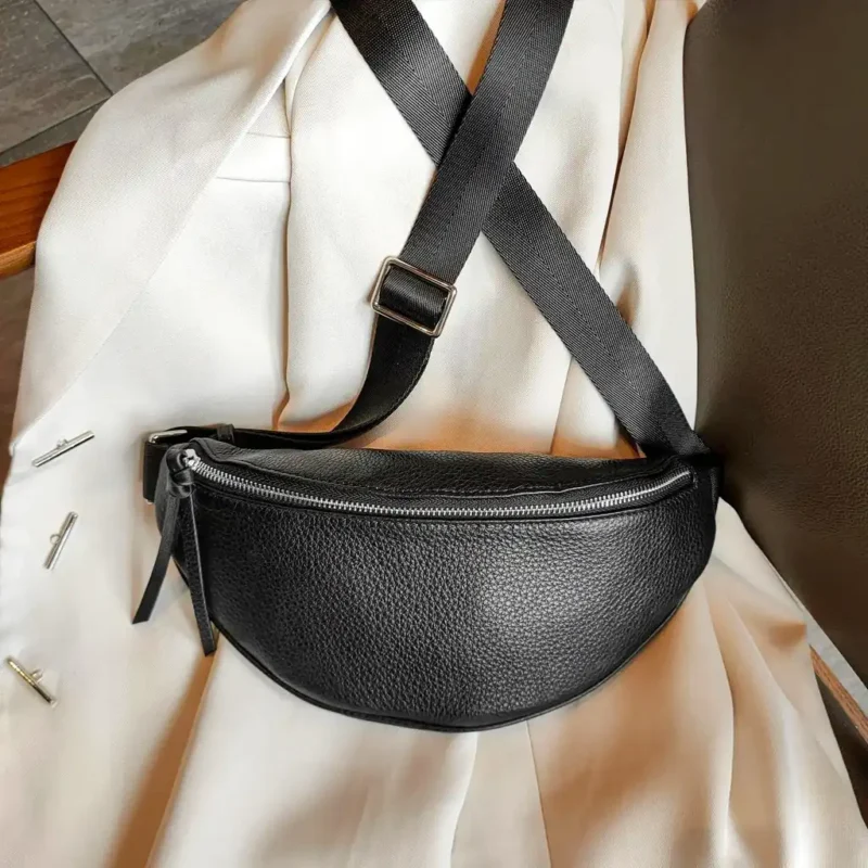 Sac banane cuir grainé noir posé à plat de face, avec sangle noire épaisse et fermeture argentée