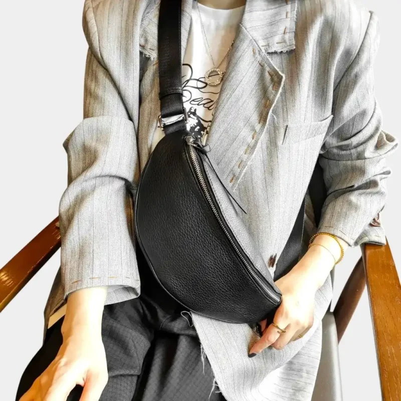Sac banane cuir grainé noir porté en bandoulière par une femme au style chic vue rapprochée