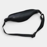 Petit sac banane cuir noir, posé à plat vue arrière, avec sangle ajustable à boucle métallique