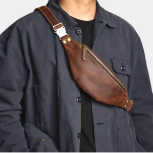 Petit sac banane en cuir marron porté en bandoulière par un homme avec boucle métallique sur la sangle