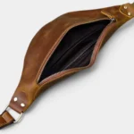 Petit sac banane cuir marron posé vue de dessus, poche principale ouverte révélant une doublure noire