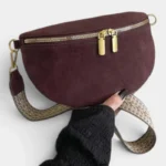 Sac banane en daim bordeaux posé de face, avec sangle à motif tressé et fermeture éclair dorée
