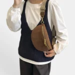 Sac banane simili cuir marron porté en bandoulière par une femme avec sangle à motifs au style chic